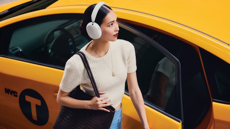 woman in white shirt next to taxi cab experiencing music through custom branded headphones