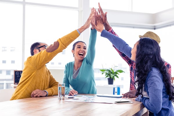 Hybrid employees celebrating a win while in the office